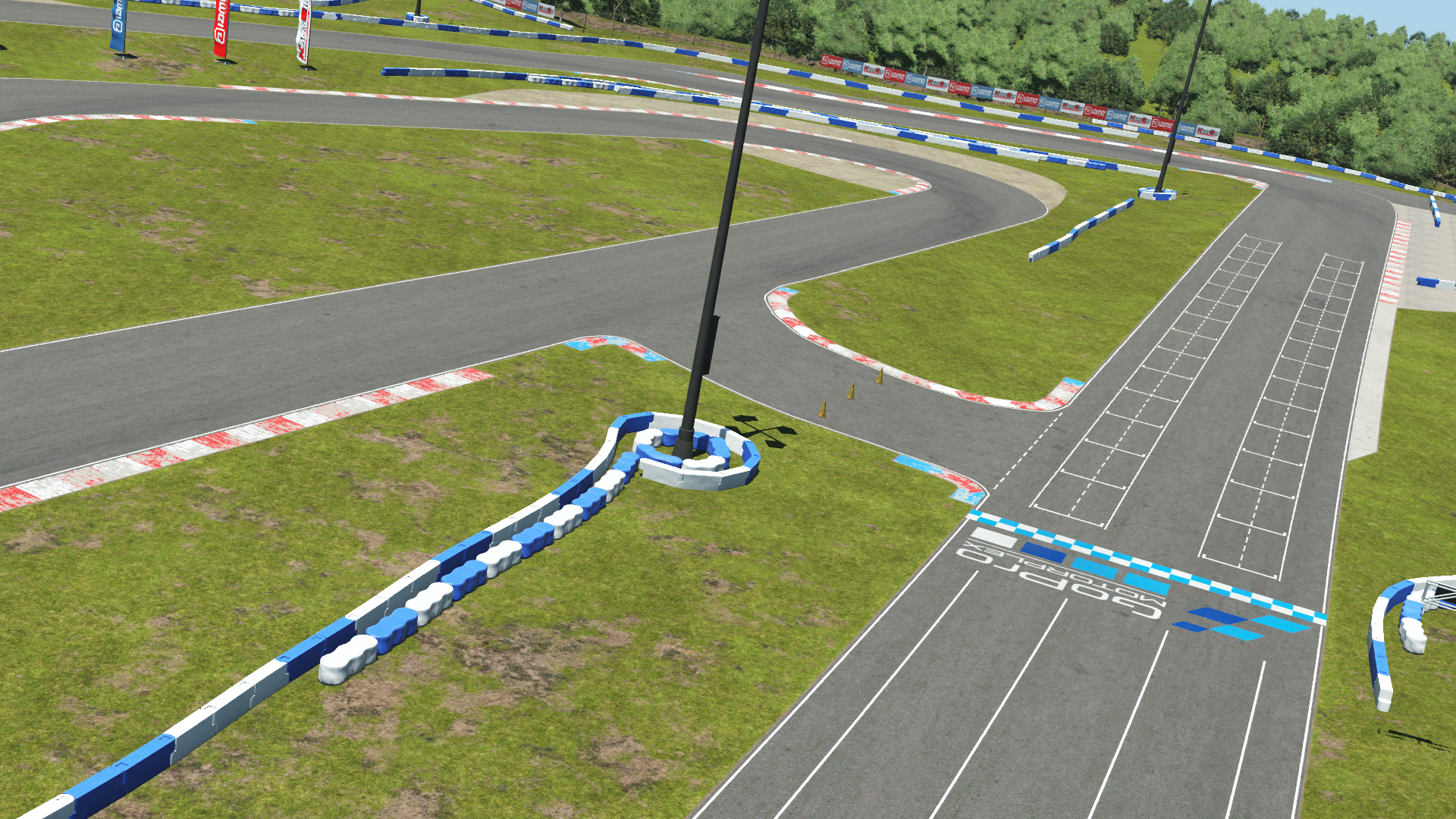 Starting grid and karting track with red and white kerbs, surrounded by grassy areas and barriers